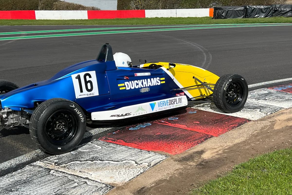 A blue and yellow Duckhams Formula Ford, number 16, on the kerb.