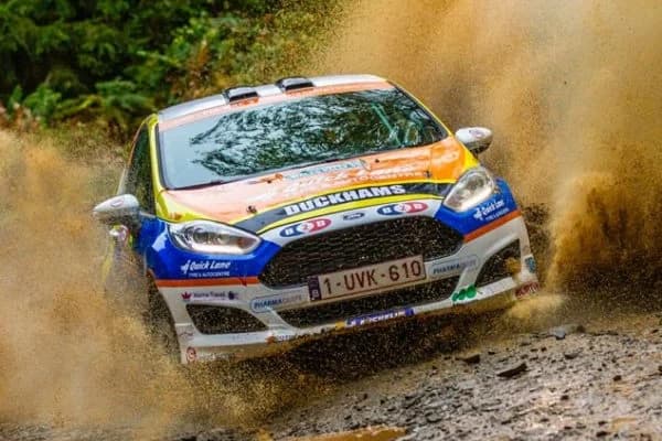 Louise Cook's Duckhams Fiesta rally car sliding through a muddy forest stage.
