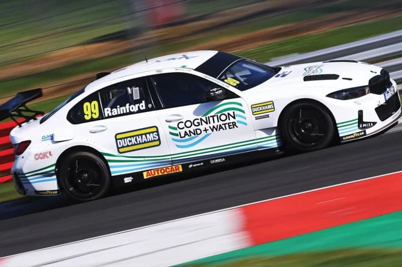 The West Surrey Racing BMW 330i, number 99, in Duckhams livery at speed.