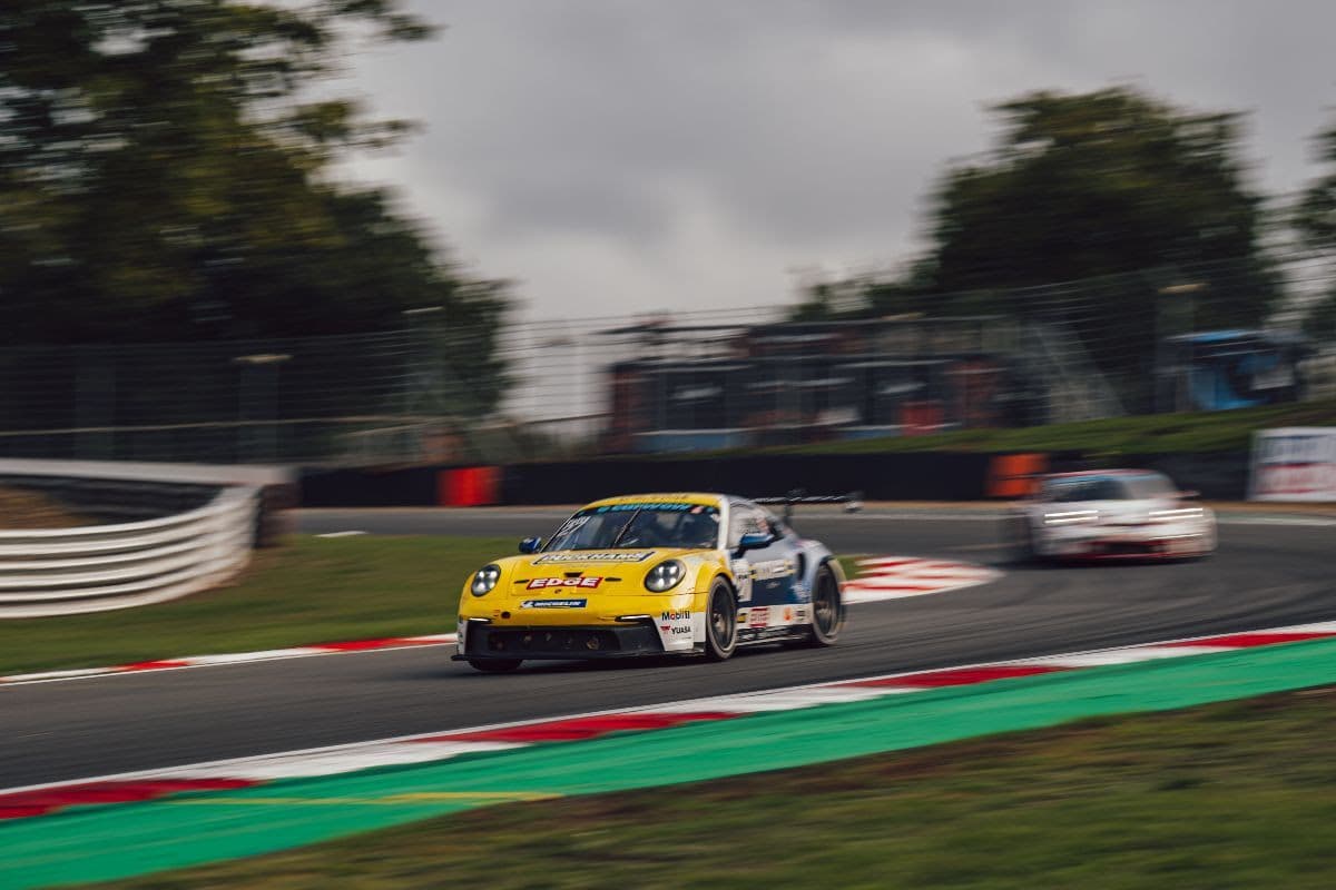 The yellow Duckhams Yuasa Racing Porsche 911 GT3 Cup car cornering at Brands Hatch, another car following behind.