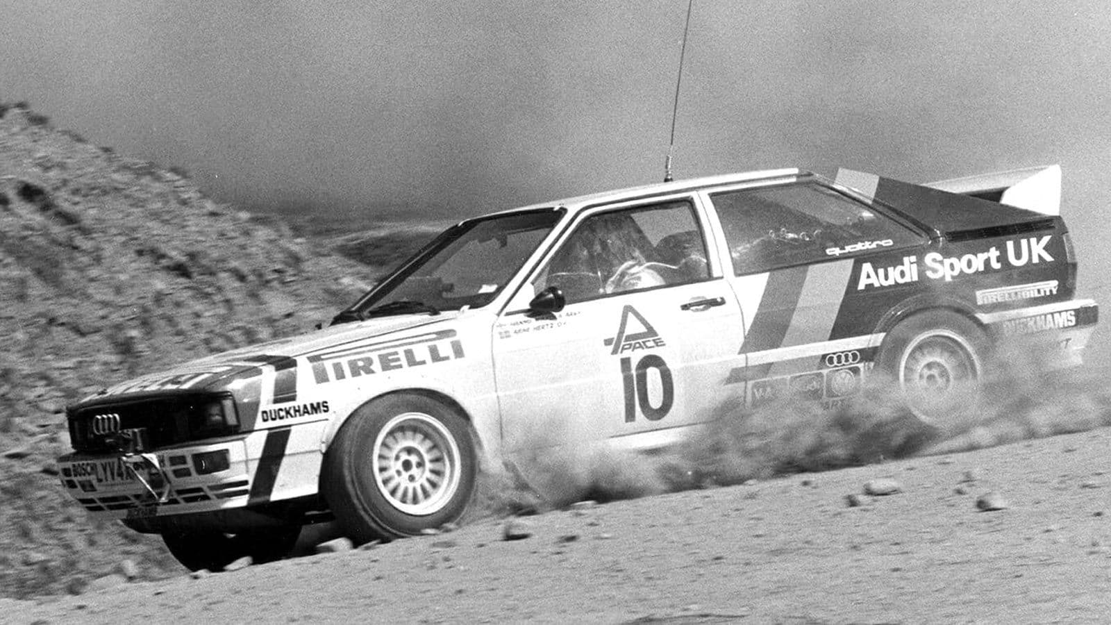 An Audi Sport UK rally car, number 10, sliding through a gravel corner.